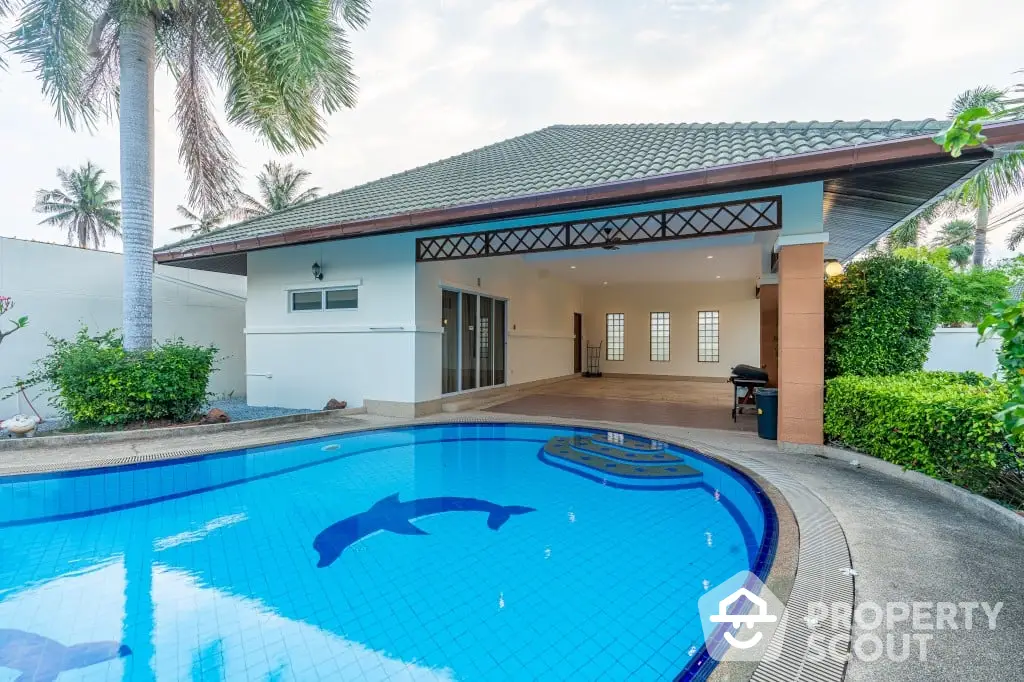 Luxurious private villa with a sparkling blue dolphin-shaped swimming pool surrounded by lush palm trees, offering a serene tropical oasis with a spacious covered patio for alfresco dining.