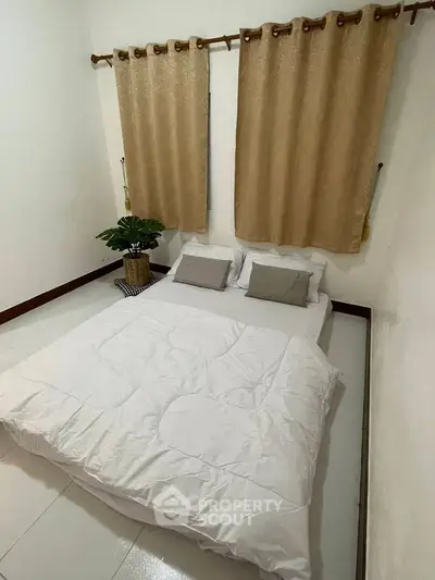 Cozy minimalist bedroom with white bedding and beige curtains, perfect for relaxation.