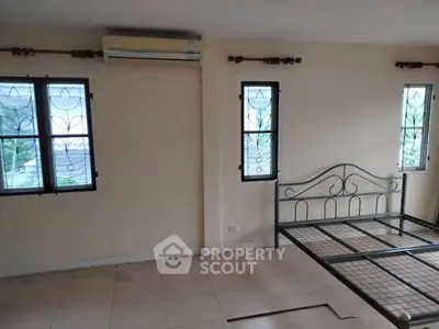 Spacious bedroom with metal bed frame and natural light from two windows.