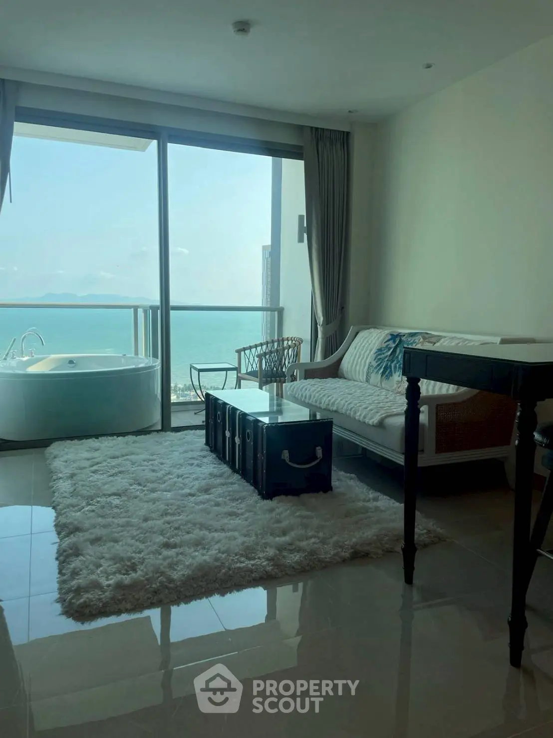 Luxurious living room with ocean view and private balcony, featuring elegant decor and plush furnishings.