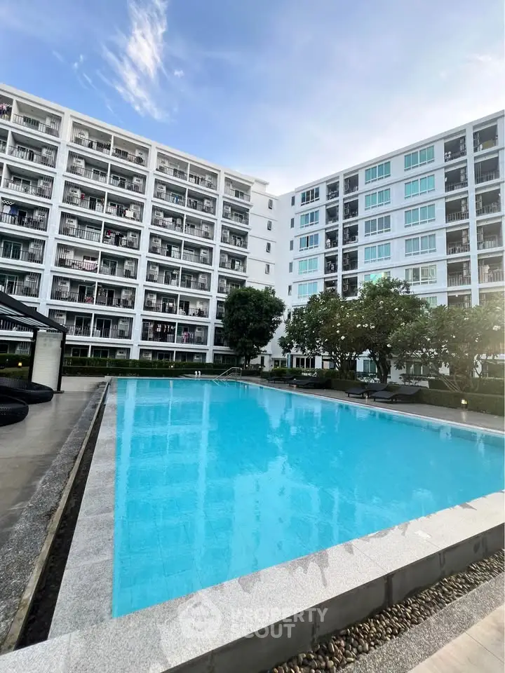 Modern apartment complex with a large swimming pool and lush greenery, perfect for luxury living.
