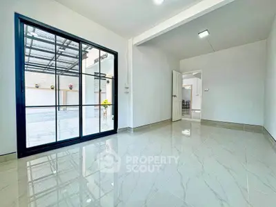 Spacious modern living room with glossy tile flooring and large glass doors.
