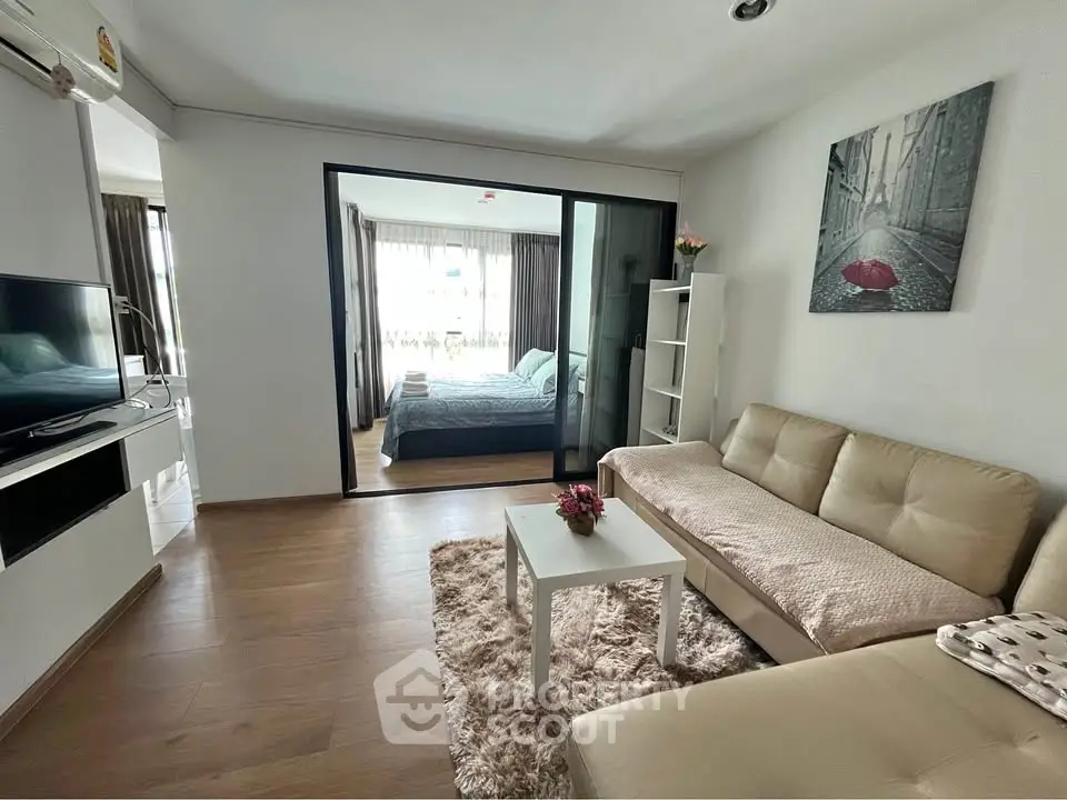 Modern living room with cozy sofa and view into stylish bedroom