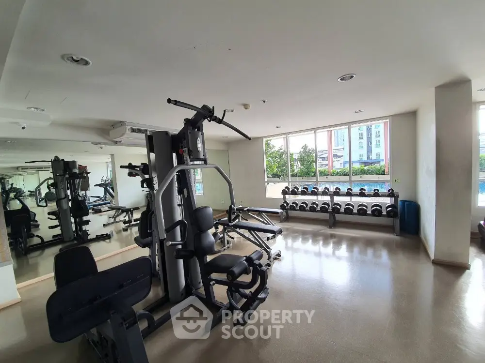 Spacious gym with modern equipment and large windows offering natural light