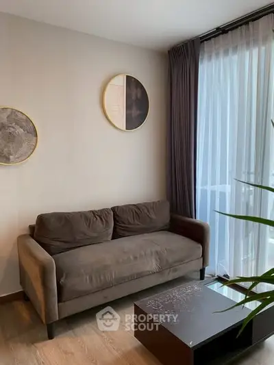 Cozy living room with modern sofa and floor-to-ceiling window drapes.