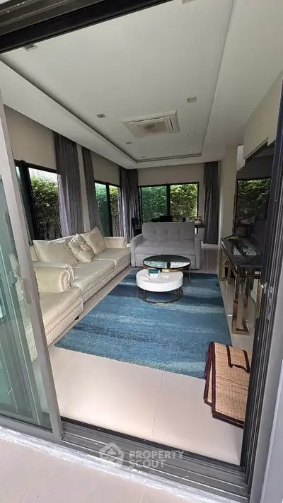 Elegant living room with plush sofas, modern decor, and large windows offering lush garden views.
