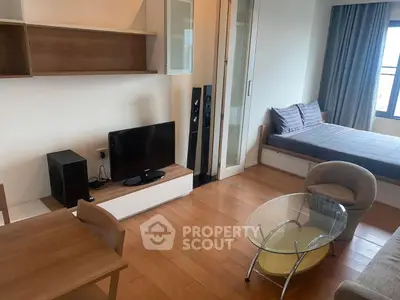 Modern studio apartment with wooden flooring, cozy seating, and natural light.