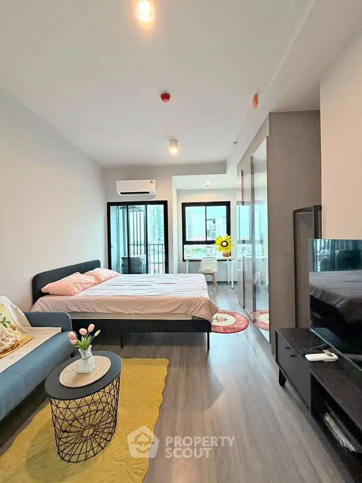 Modern studio apartment with stylish decor and natural light, featuring a cozy bed and sleek furnishings.