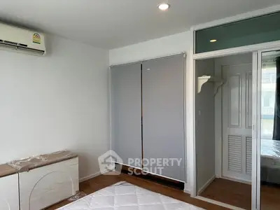 Modern bedroom with air conditioning and wooden flooring, featuring a sliding door to an adjacent room.
