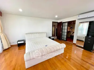 Spacious bedroom with wooden flooring and modern furnishings in a luxurious apartment.