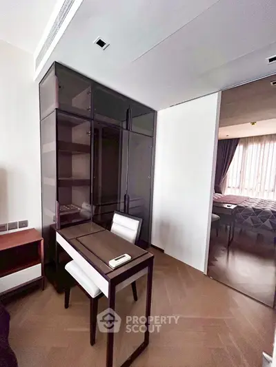 Modern study area with sleek desk and chair, adjacent to a cozy bedroom with natural light.