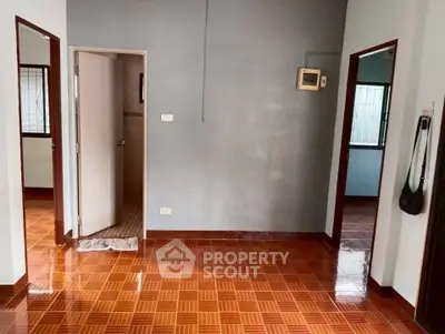 Spacious interior with tiled flooring and multiple doorways in a well-lit room.