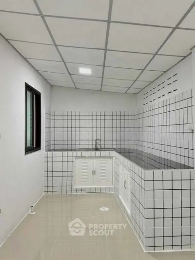 Modern kitchen with tiled walls and sleek cabinetry in a minimalist design.