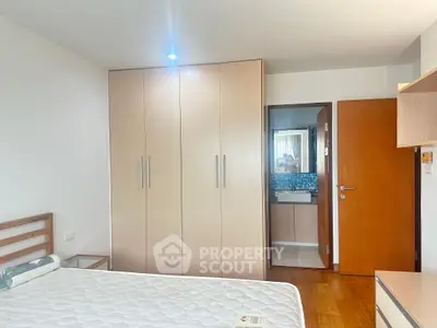 Spacious bedroom with wooden flooring and built-in wardrobe in modern apartment.