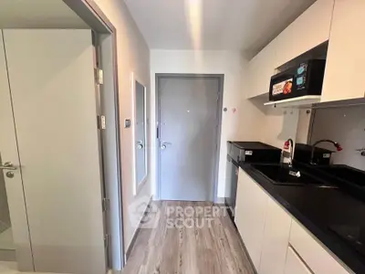 Modern kitchen with sleek cabinetry and built-in microwave in a compact apartment.