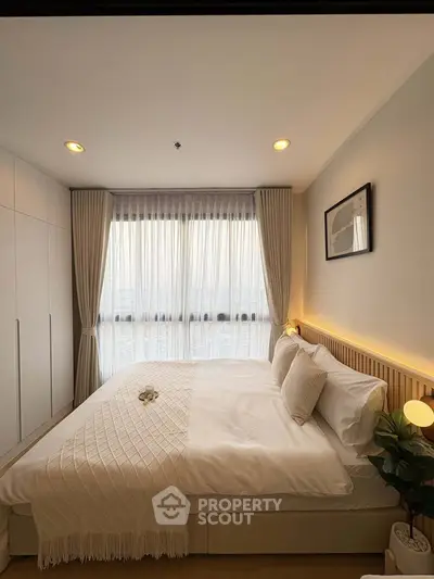 Cozy bedroom with elegant decor and large window offering natural light