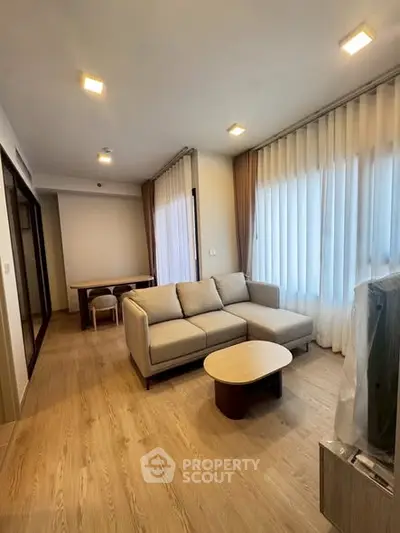 Spacious modern living room with elegant wooden flooring and cozy sofa in a well-lit apartment.