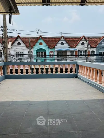 Charming balcony with tiled flooring and colorful townhouse view, perfect for relaxation.