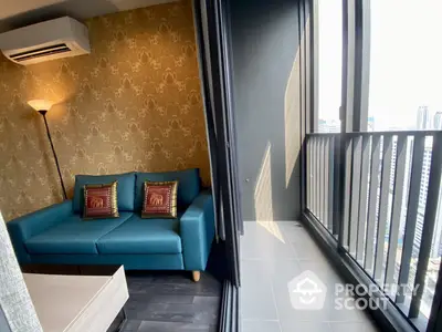 Chic high-rise corner unit with a plush blue sofa, patterned wallpaper, and floor-to-ceiling windows leading to a balcony with a city view.