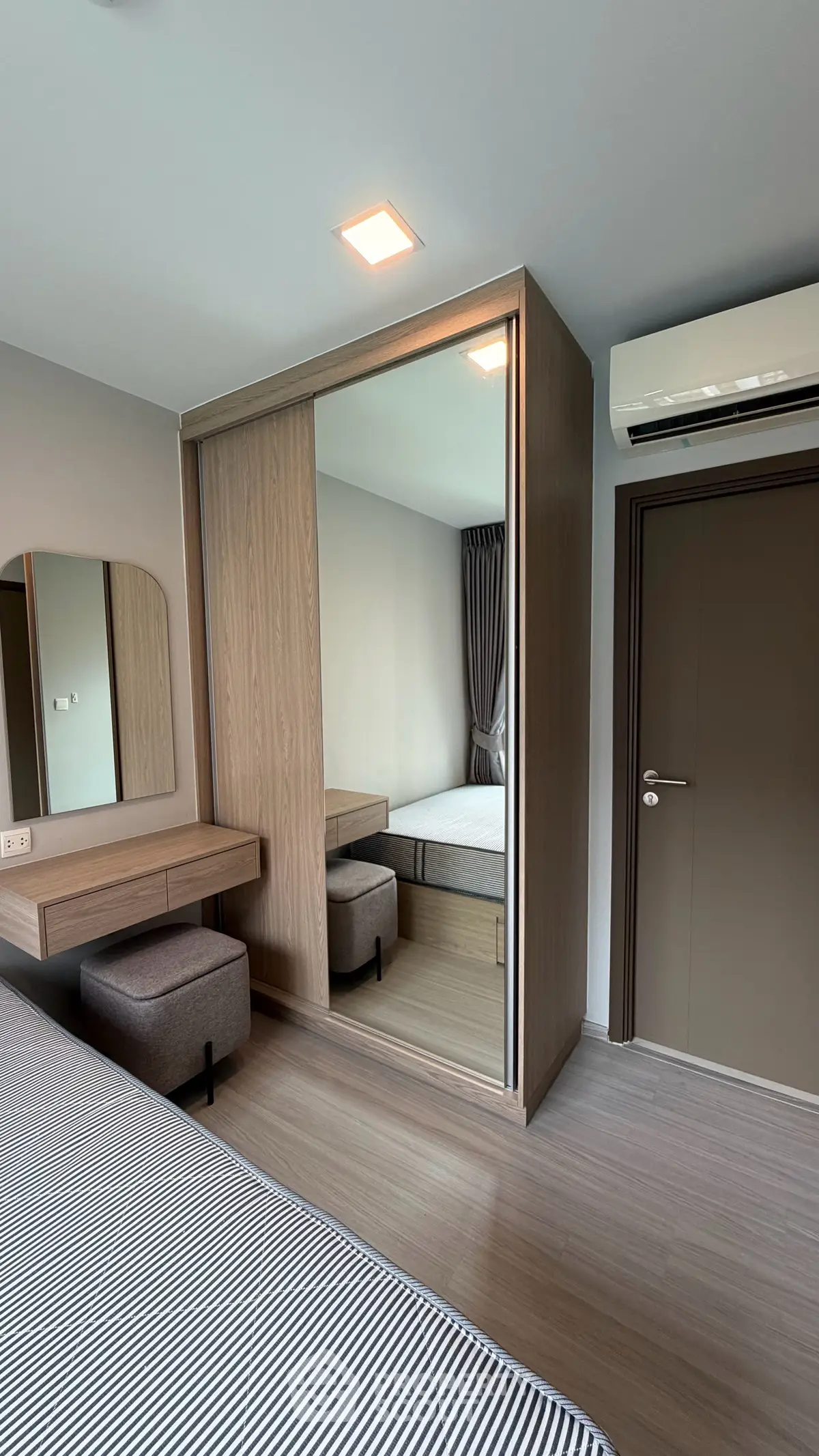 Modern bedroom with mirrored wardrobe and air conditioning in stylish apartment.