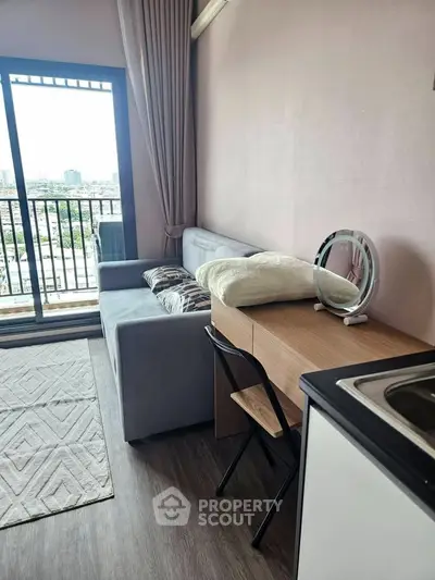 Modern living room with city view, featuring a cozy sofa, desk, and balcony access.