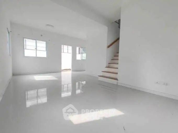 Spacious minimalist living room with glossy white flooring and staircase