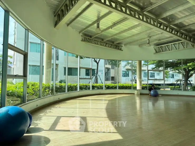 Spacious gym with large windows and exercise balls, offering a bright and airy workout space.