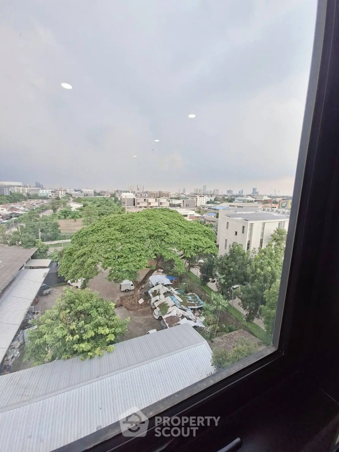 Stunning cityscape view from a high-rise window, showcasing urban skyline and lush greenery.