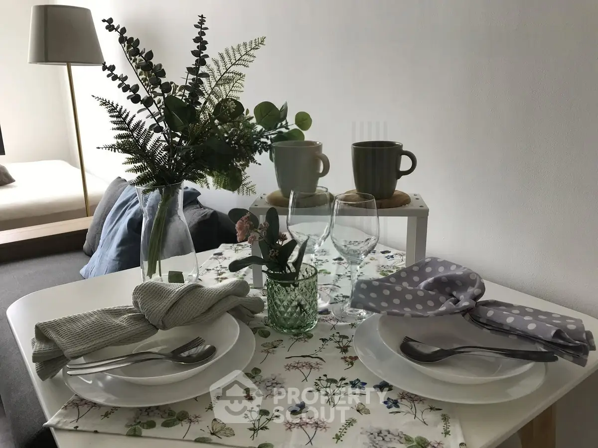 Charming dining setup in cozy living space with elegant tableware and lush greenery accents.