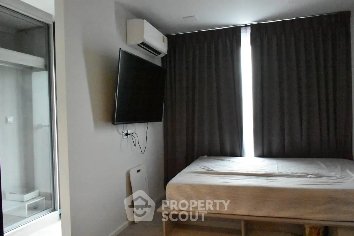 Modern bedroom with wall-mounted TV and air conditioning, featuring sleek design and natural light.