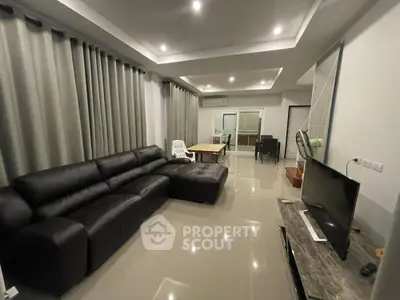 Spacious modern living room with sleek black leather sofa and elegant lighting.