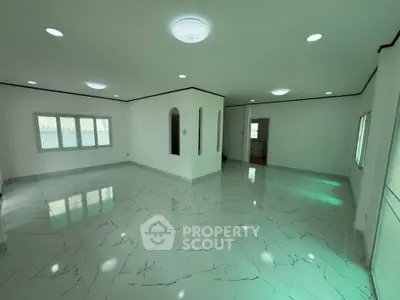 Spacious modern living room with elegant marble flooring and ample natural light.