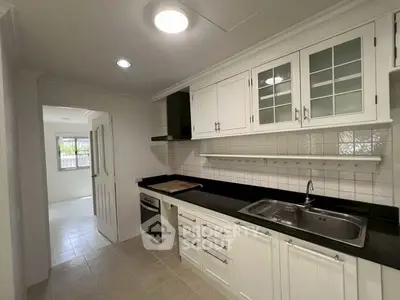 Modern kitchen with sleek black countertops and white cabinetry, featuring built-in oven and ample storage space.