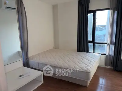 Spacious bedroom with large window and natural light, featuring a comfortable bed and modern decor.