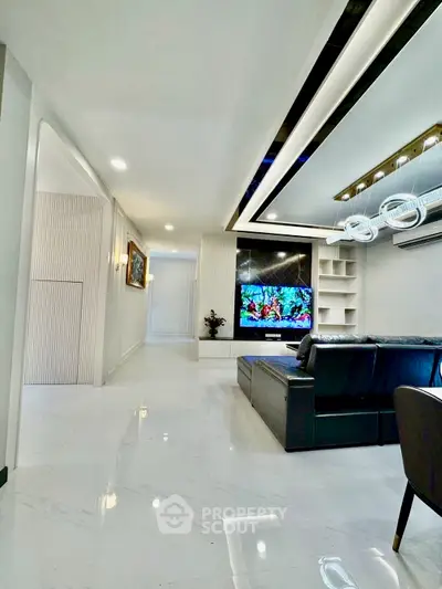 Luxurious modern living room with sleek design and high-end finishes, featuring a large TV and stylish lighting.