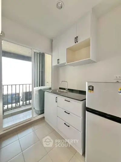 Modern kitchen with sleek white cabinets and balcony access, perfect for urban living.