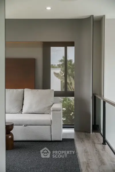 Modern living room with sleek design and large window offering natural light and scenic view.