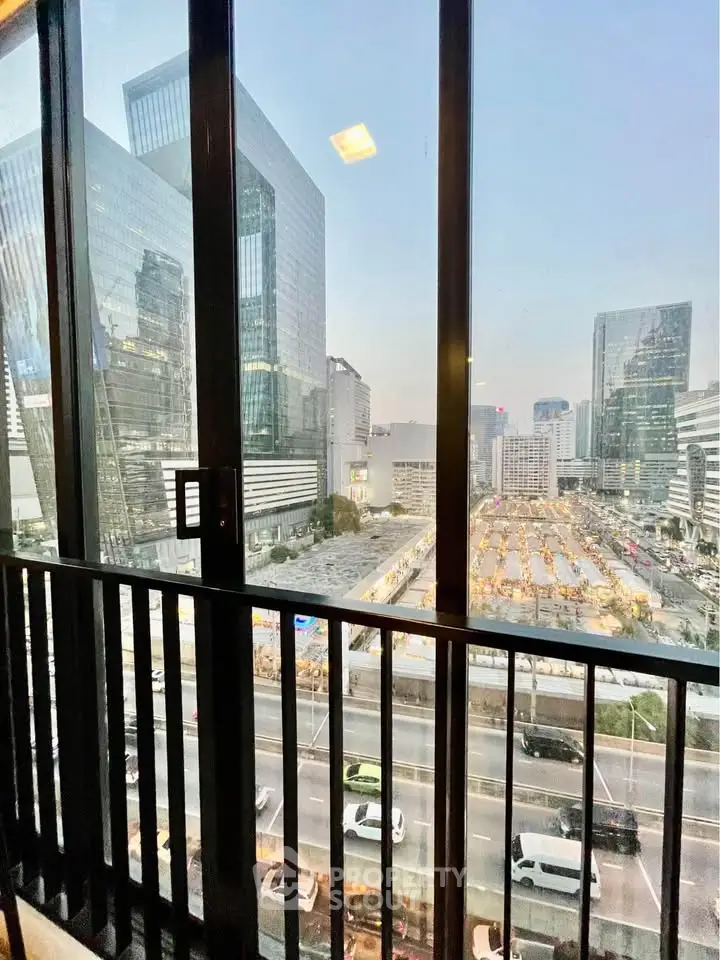 Stunning urban view from a high-rise balcony overlooking city skyline and busy streets.