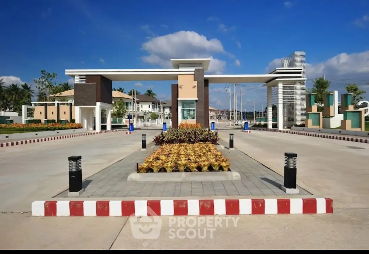 Modern gated community entrance with landscaped garden and clear blue sky.