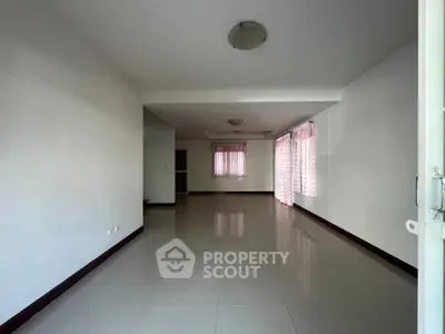 Spacious empty living room with large windows and tiled flooring, perfect for customization.