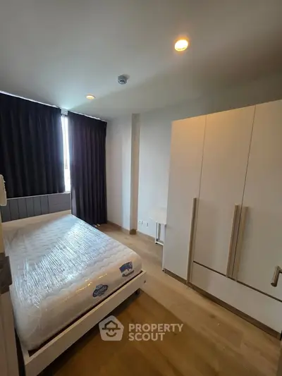 Modern bedroom with natural light, featuring a new mattress and sleek wardrobe, ideal for comfortable living.