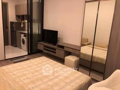 Modern bedroom with mirrored wardrobe and compact kitchen area featuring a washing machine.