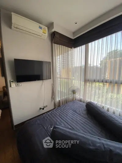 Cozy bedroom with large windows and modern amenities in a stylish apartment.