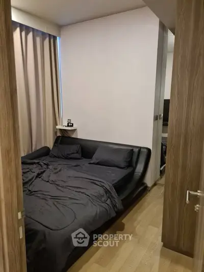 Cozy bedroom with modern black bedding and wooden flooring, perfect for restful nights.
