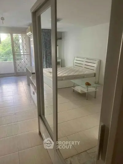 Spacious bedroom with large windows and balcony access, featuring modern furniture and natural light.