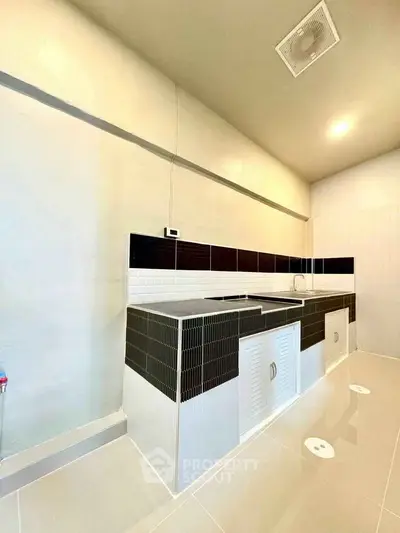 Modern kitchen with sleek black and white tile design and ample counter space.