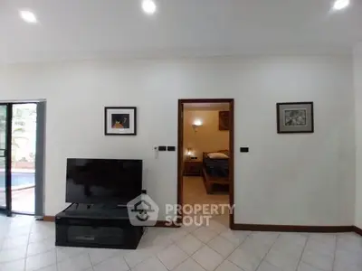Spacious living room with TV and view into cozy bedroom, ideal for modern living.