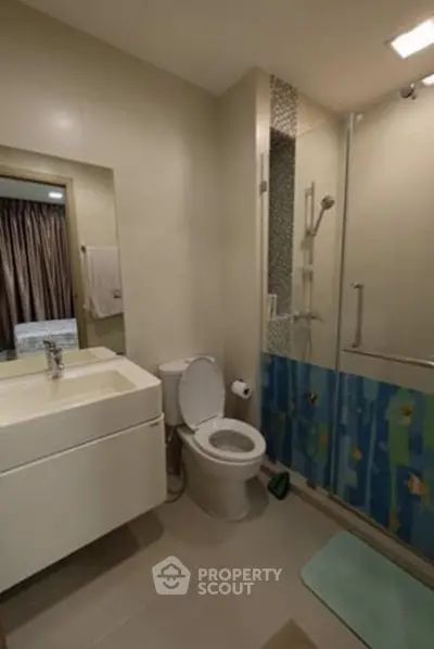 Modern bathroom with glass shower and sleek vanity in a cozy apartment.