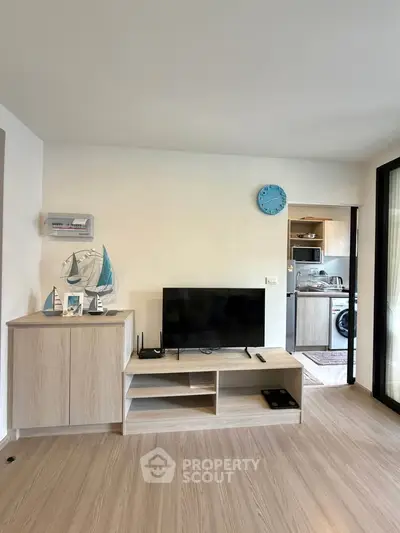 Modern living room with stylish decor and open kitchen view, featuring sleek wooden flooring and contemporary furniture.