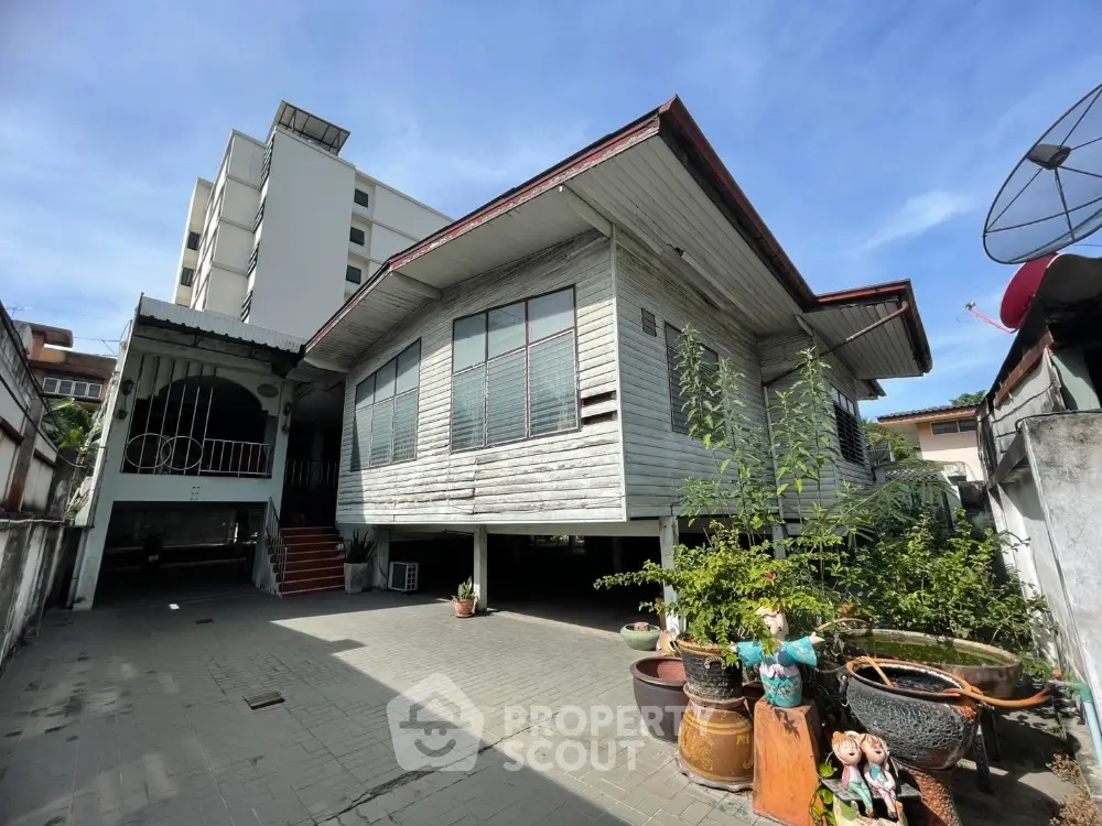 Charming traditional wooden house with spacious front yard and potted plants, perfect for serene living.